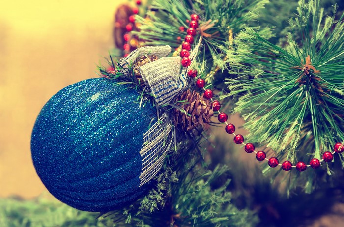 Blue Christmas ornament on a pine tree with red beads