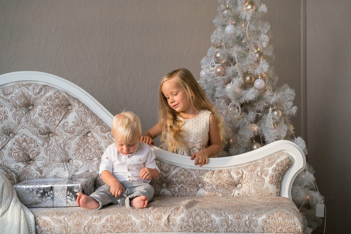 Children with Christmas tree and gifts on sofa