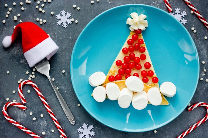 Christmas tree pancake with berries and marshmallows on a plate