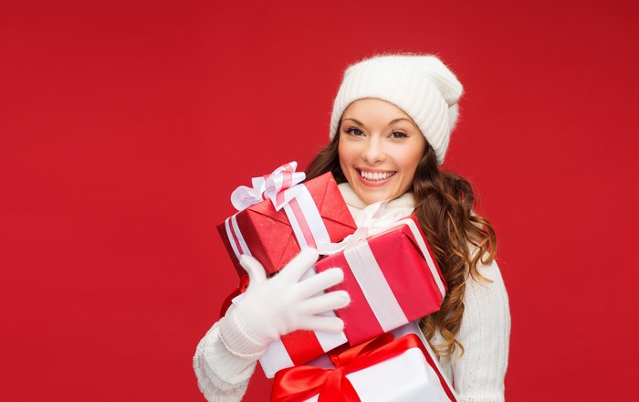 Woman in winter hat holding Christmas gifts