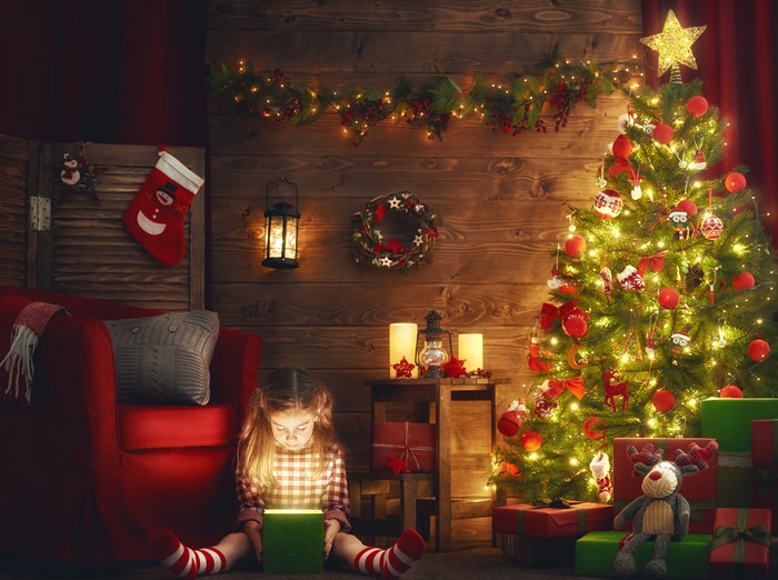 Girl opening a glowing Christmas gift by the tree