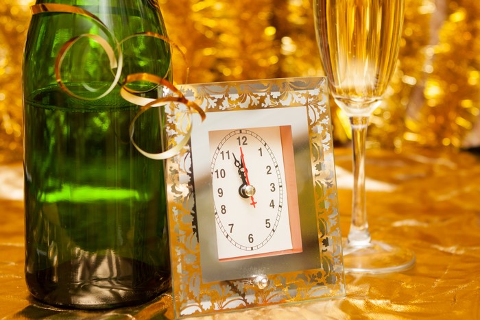 Champagne bottle, clock, and glass on gold background