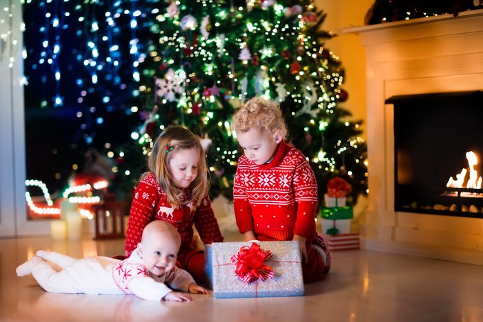 Three Children Opening Christmas Gifts by the Tree