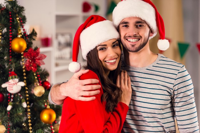 Couple in Santa hats by Christmas tree