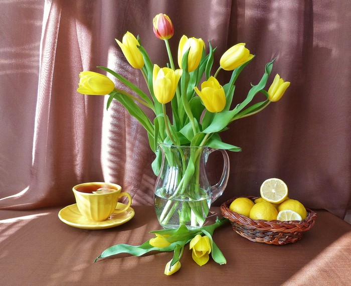 Yellow tulips in a vase with lemons and tea