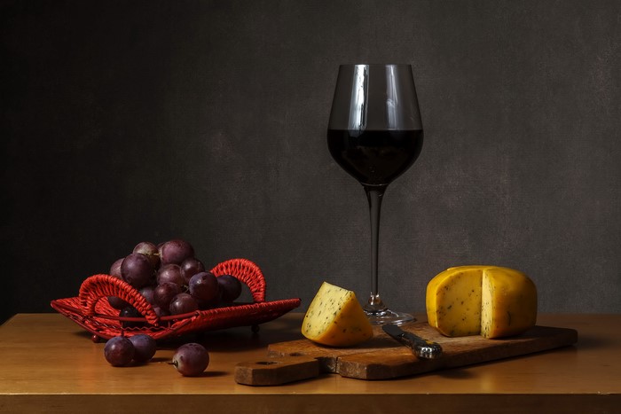Still-life with wine, grapes, and cheese on a cutting board