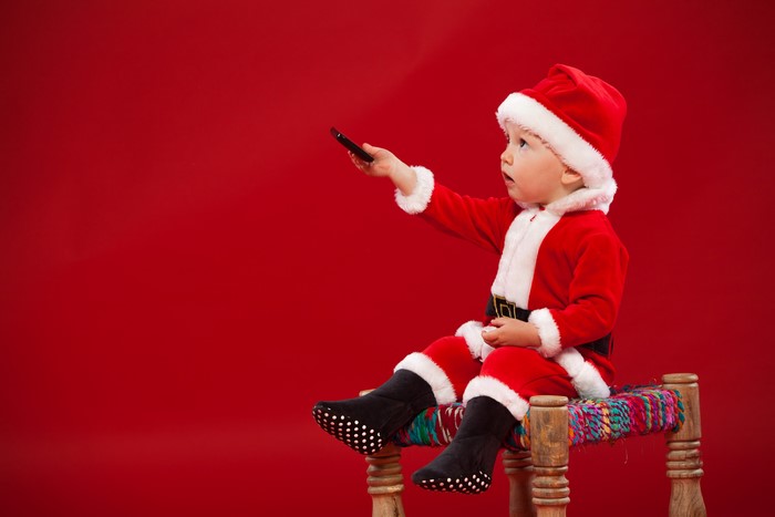 Boy in Santa costume holding a remote