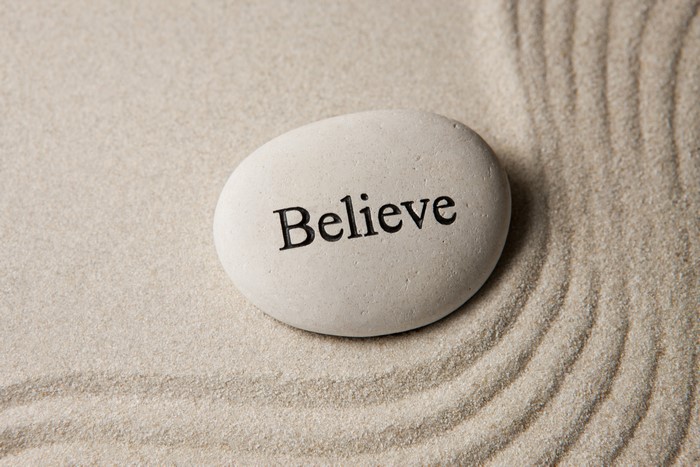 Stone with the word Believe on sand