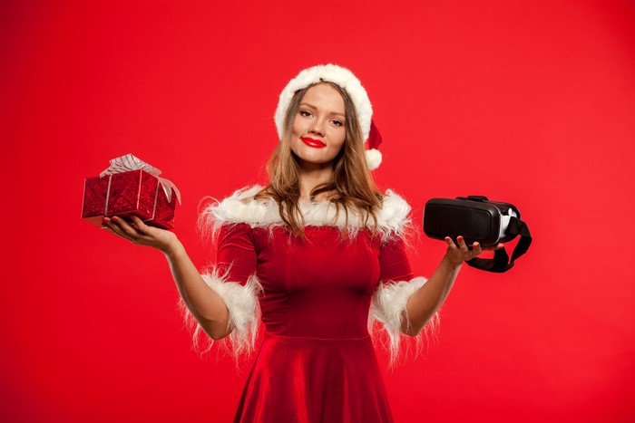 Woman in Santa outfit holding gift and VR headset