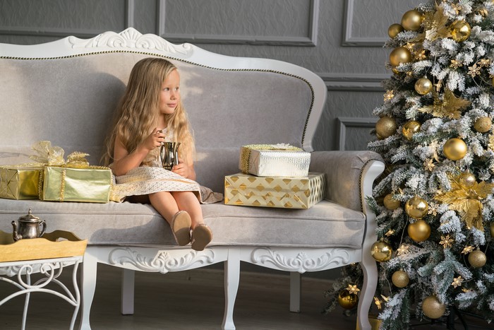 Girl Sitting on Sofa with Christmas Tree and Gifts