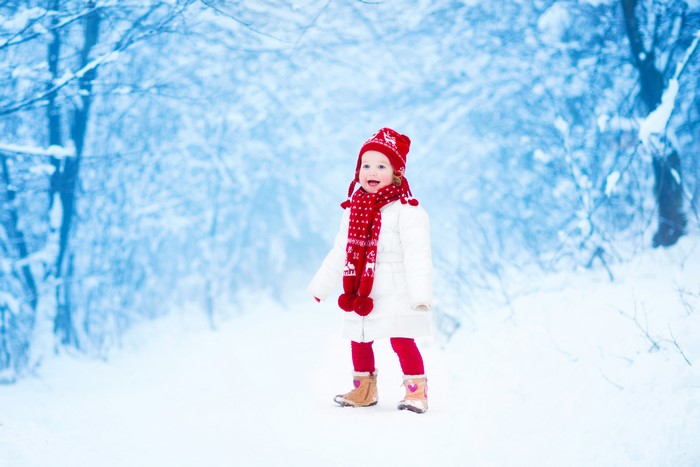 Little girl in winter hat and scarf in snow