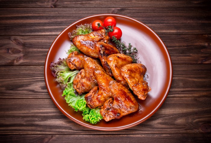 Roasted chicken wings on a plate with tomatoes and lettuce