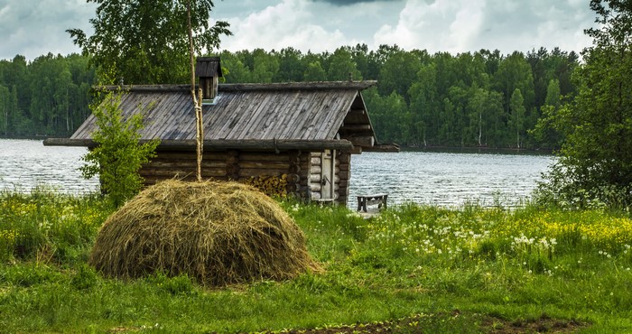 Wooden house by a lake with a haystack in Russia
