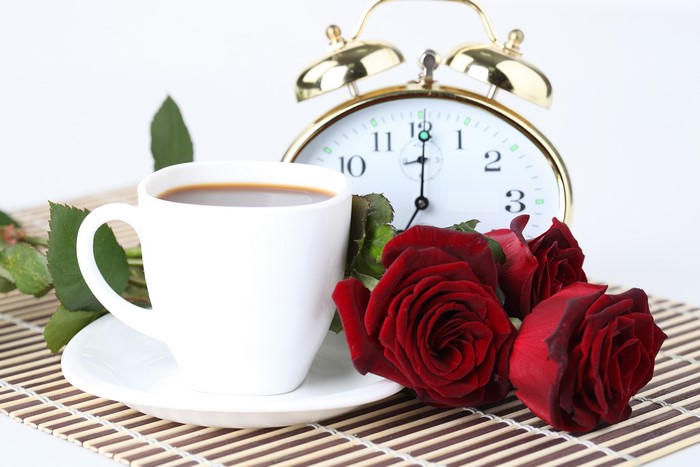 Coffee cup with red roses and alarm clock