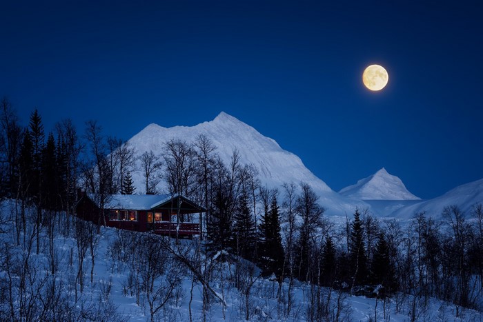 Cabin in snowy mountains under the full moon
