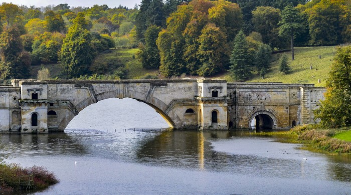 Stone bridge over a river in Blenheim Park, England during autumn