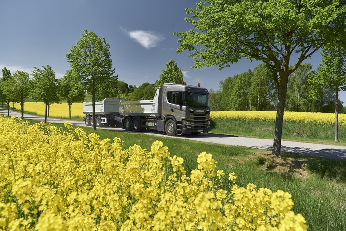 Scania truck driving on a road with canola fields