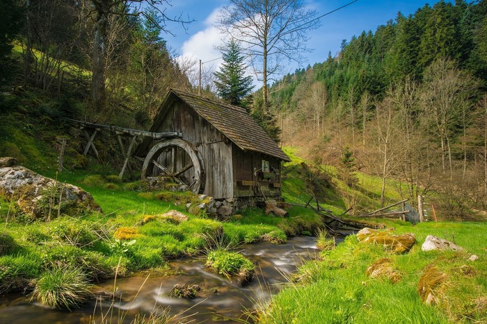 Old watermill by a stream in a forest