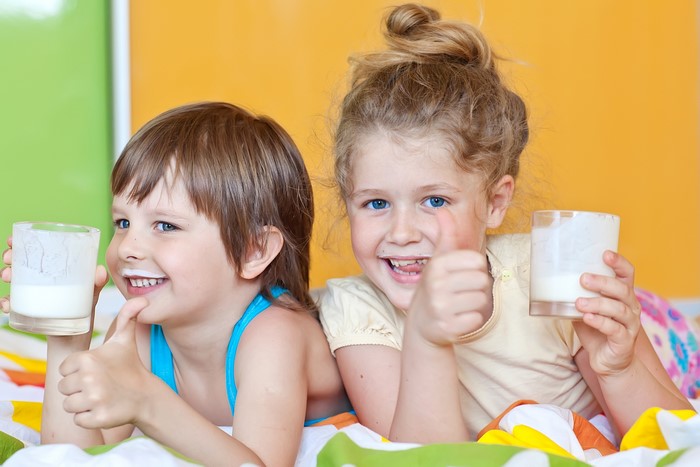 Two children with glasses of milk giving thumbs up