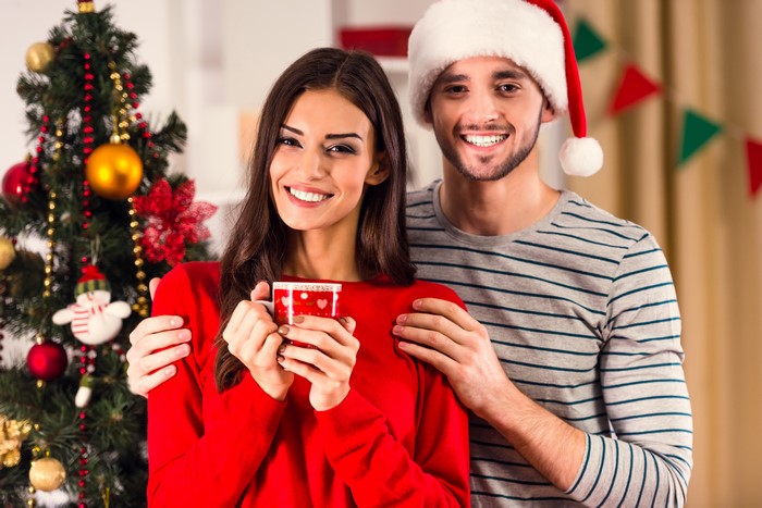 Couple in Santa hats by Christmas tree