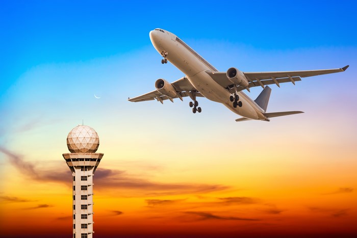 Airplane taking off near control tower at sunset