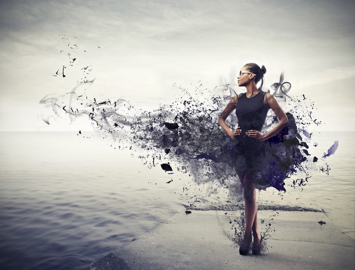 Woman in black dress dissolving into particles