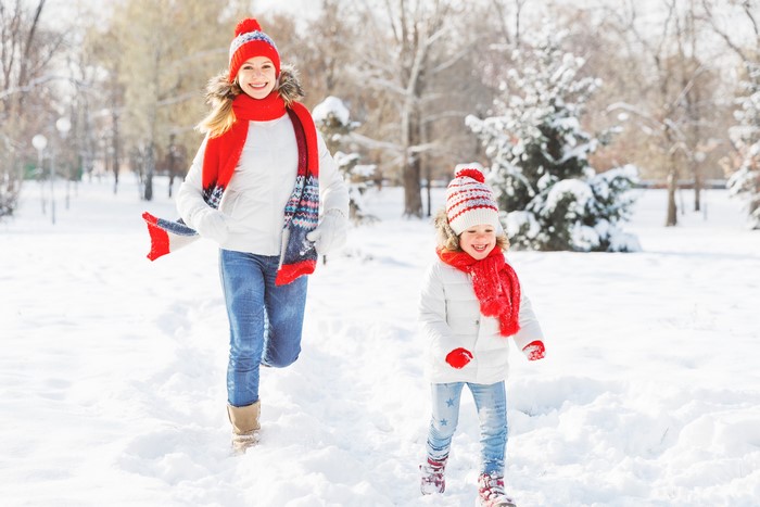 Two girls in winter clothes running in the snow