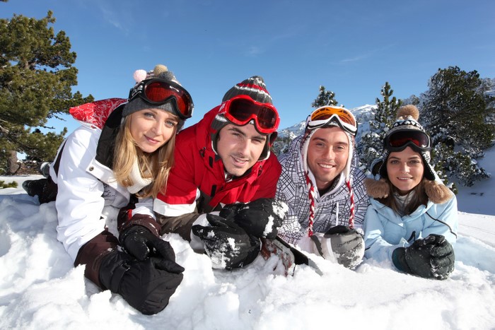 Four friends in ski gear lying in the snow