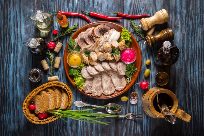 Meat platter with bread and condiments on wooden table