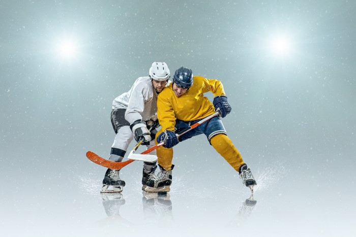 Two men playing hockey in uniform and helmets
