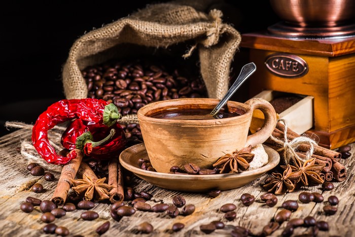 Coffee beans, cup, and spices on a wooden table