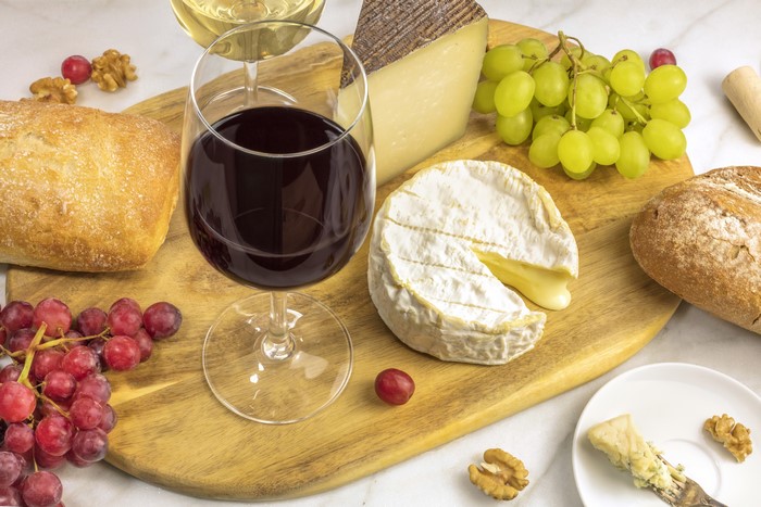 Wine, Grapes, Cheese, and Bread on a Cutting Board