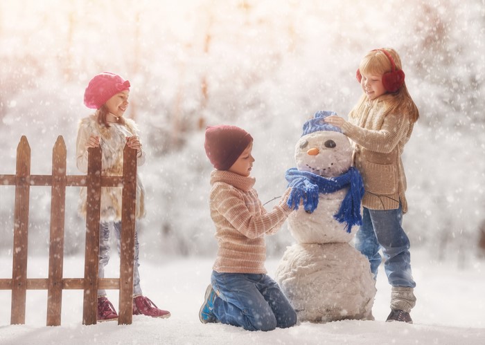 Three Children Building a Snowman in Winter