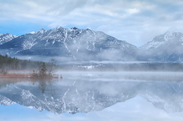 Misty lake reflecting snow-capped mountains in Bavaria