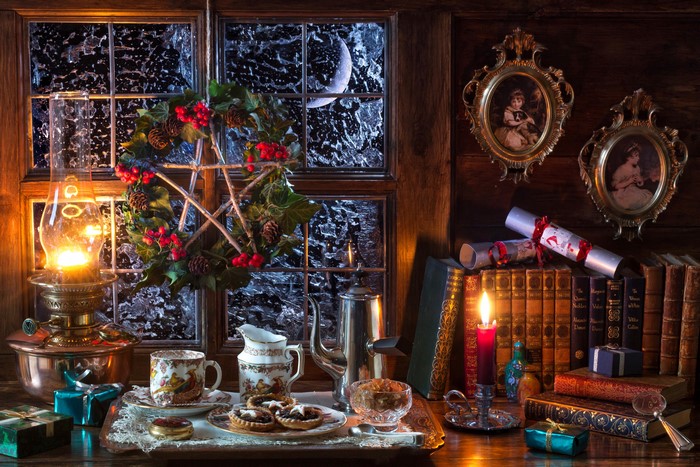 Christmas still-life with a kerosene lamp, books, and treats