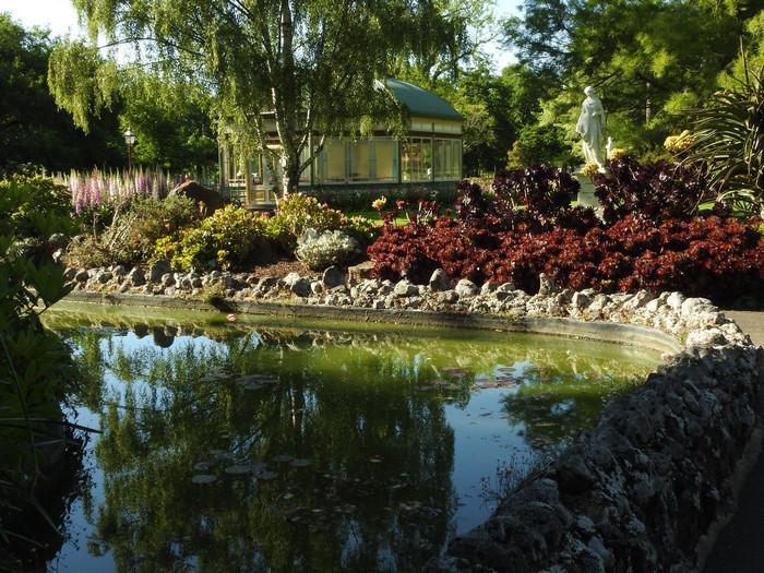 Ballarat Botanic Gardens pond with greenhouse and sculpture