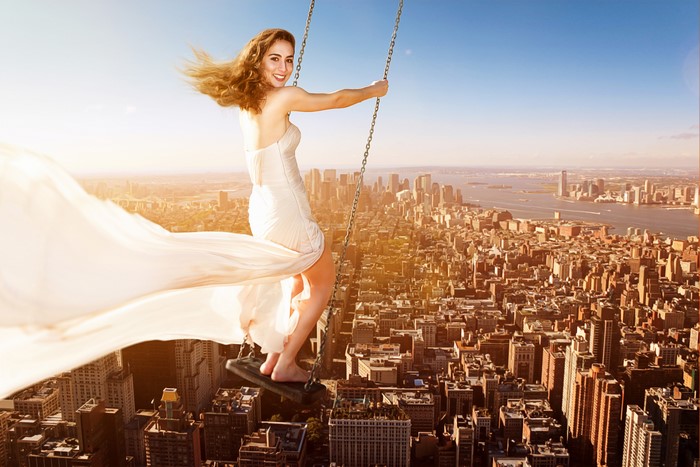 Woman on a swing over a city