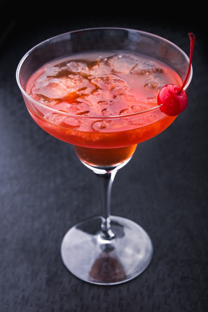 Cocktail with cherry garnish in a coupe glass