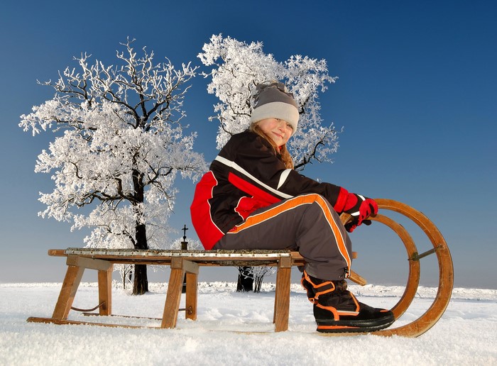 Girl on a sled in the snow with frosted trees