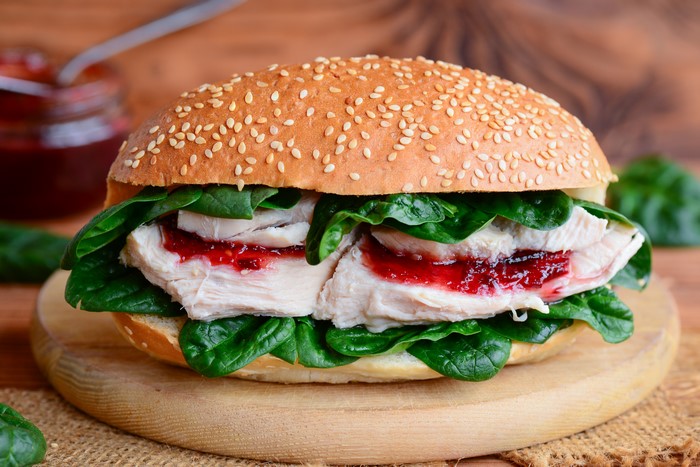 Sandwich with turkey, spinach, and cranberry sauce on a bun