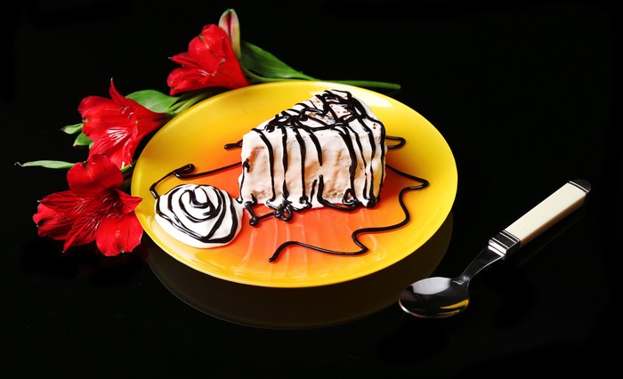 Slice of cake with chocolate drizzle and alstroemeria flowers