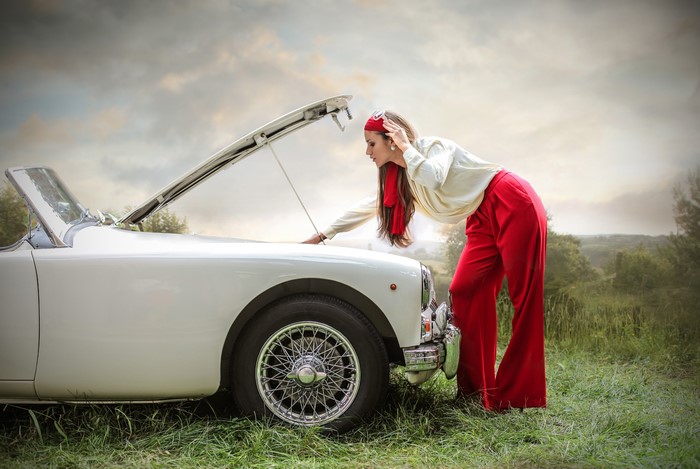 Woman looking at open car hood
