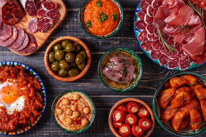 Tapas spread with cured meats, olives, and fried egg