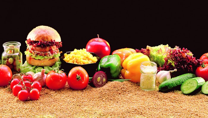 Hamburger and fresh vegetables on a grain background