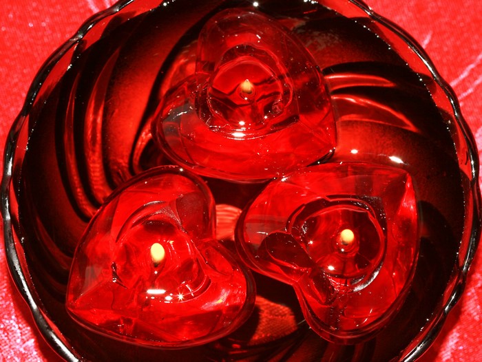 Three red heart-shaped candles in a bowl