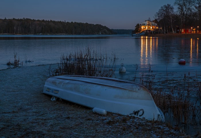 Upside down boat on frozen lake at dusk in Sweden