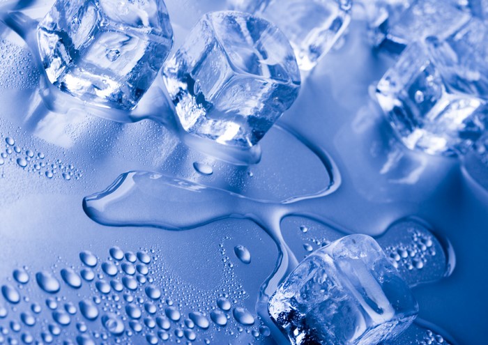 Ice cubes melting on a blue surface with water droplets