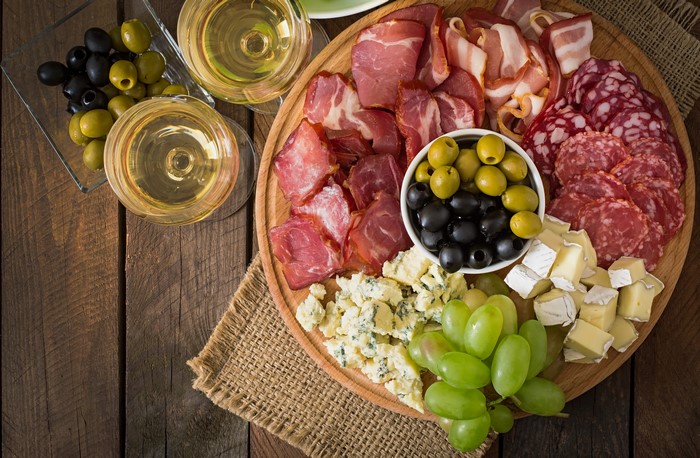 Charcuterie board with wine, olives, grapes, and cheese