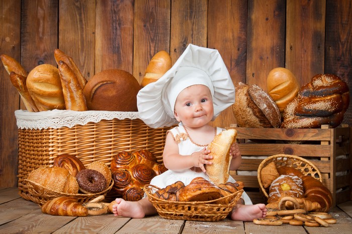 Baby in chef hat with bread and pastries