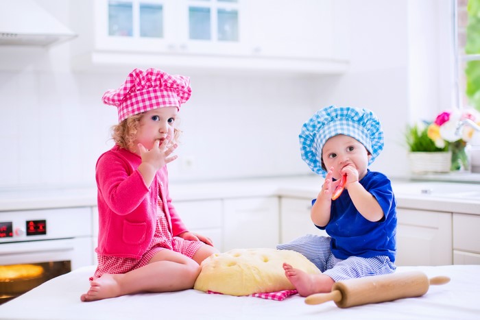 Two children in chef hats with dough